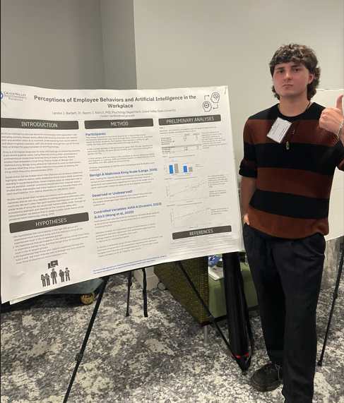 Landon Bartlett (McNair Scholar) standing next to his research poster holding his thumb up